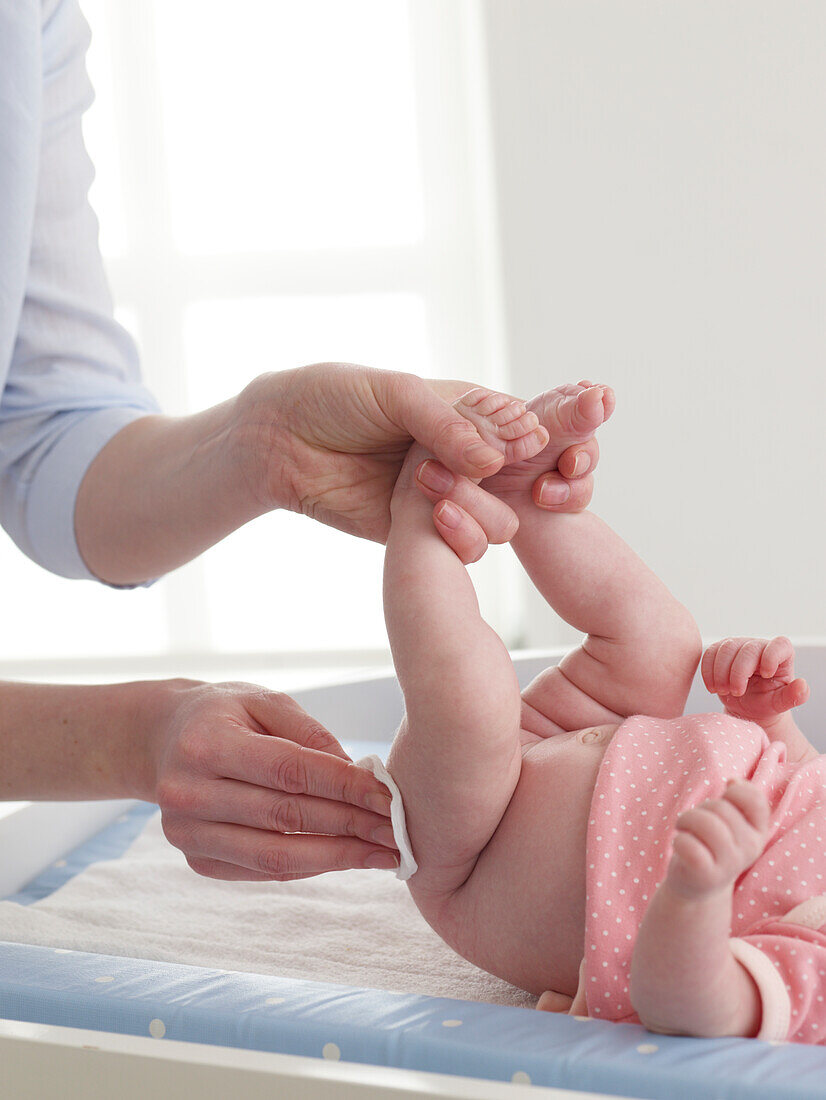 Wiping a baby girl's bottom with a cotton pad