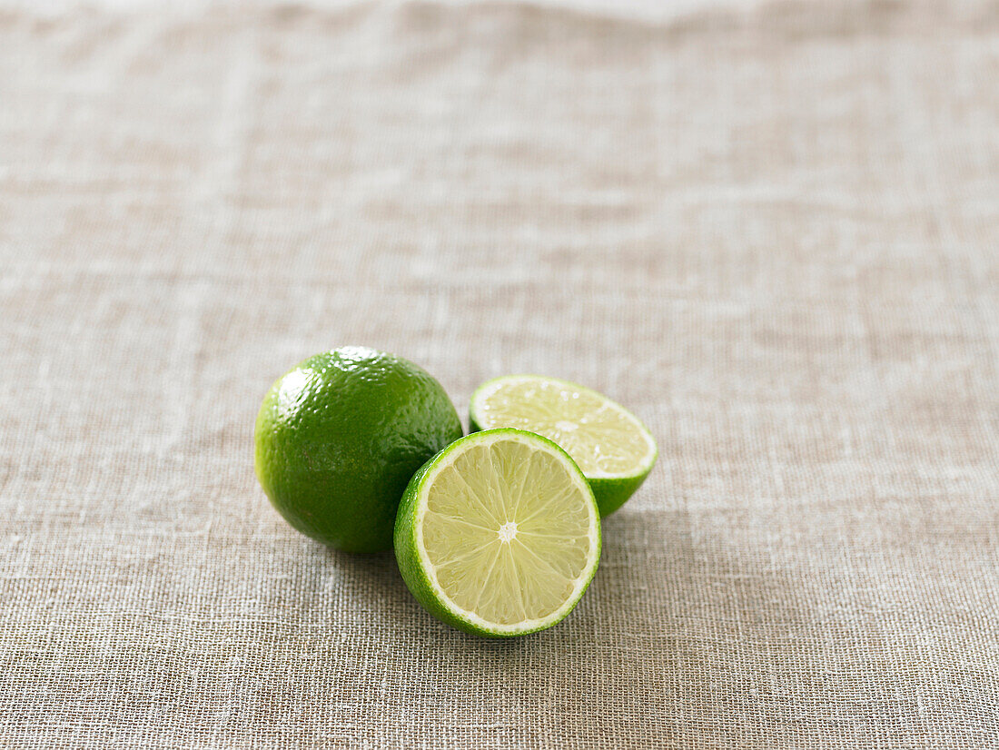 Whole and halved limes on tablecloth