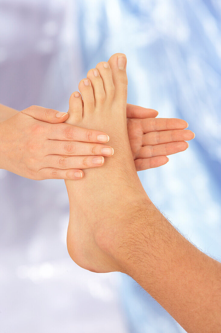 Reflexologist performing side-to-side rub on man's foot