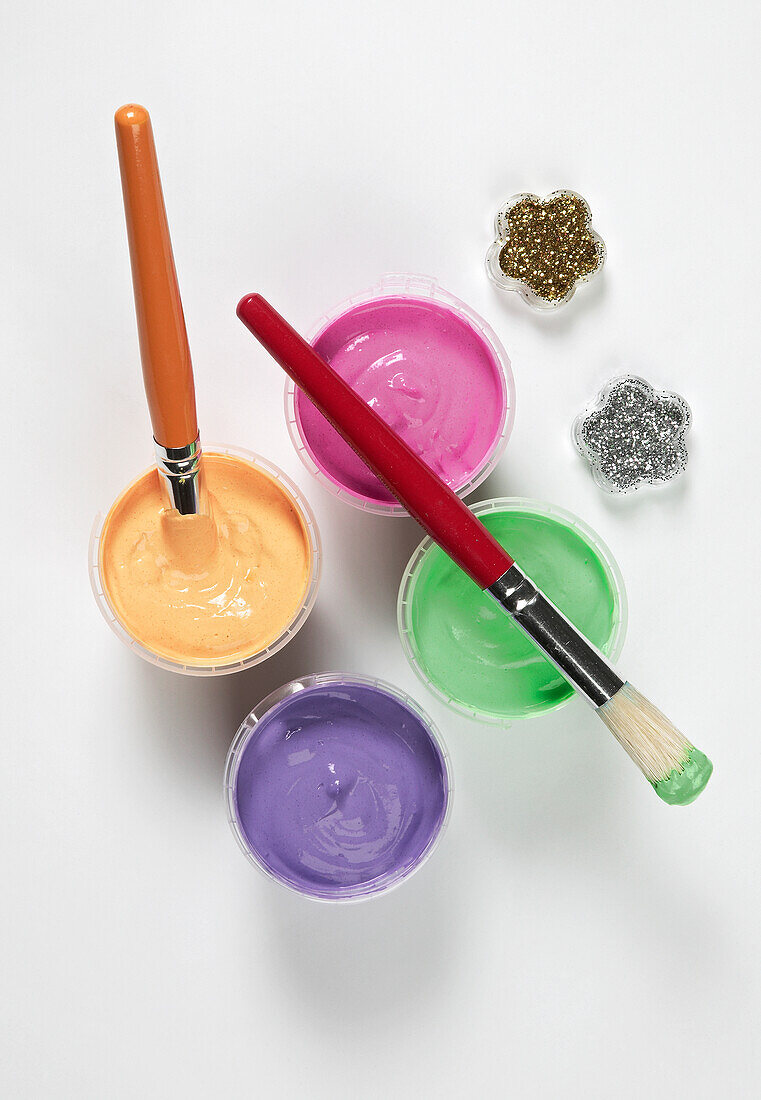 Pots of colourful paints, paintbrushes and glitter