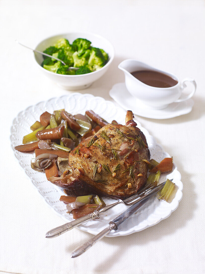 Slow pot roast lamb served on a platter, gravy and broccoli