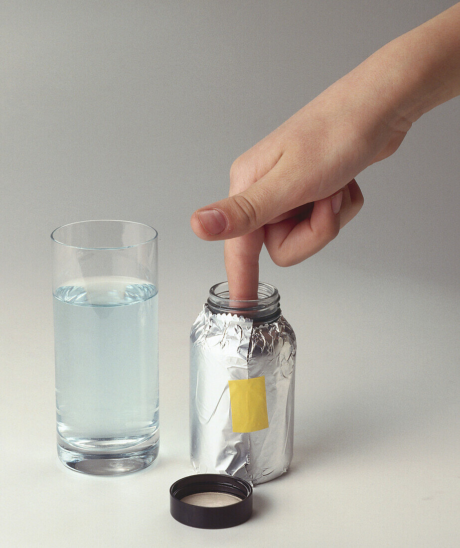 Finger being held in foil-wrapped jar