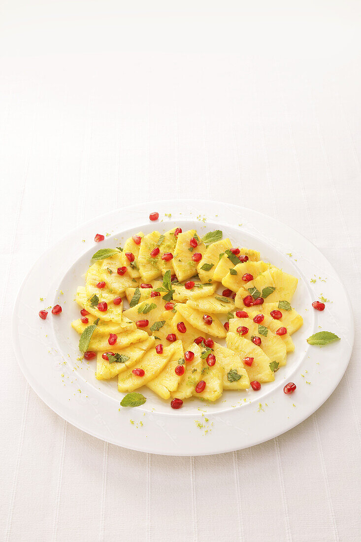 Fruit platter with slices of pineapple, pomegranates and mint