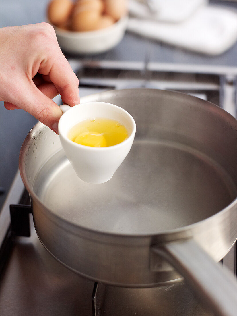 Egg in cup about to be tipped into hot water