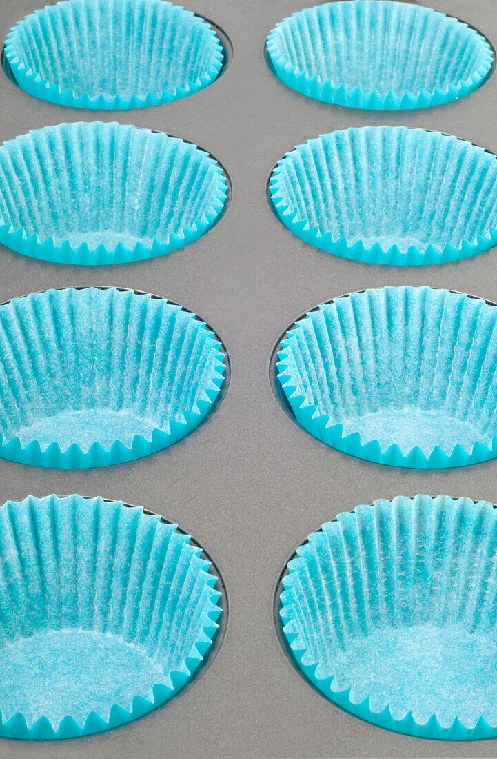Row of cake cases on stainless steel non-stick baking tray