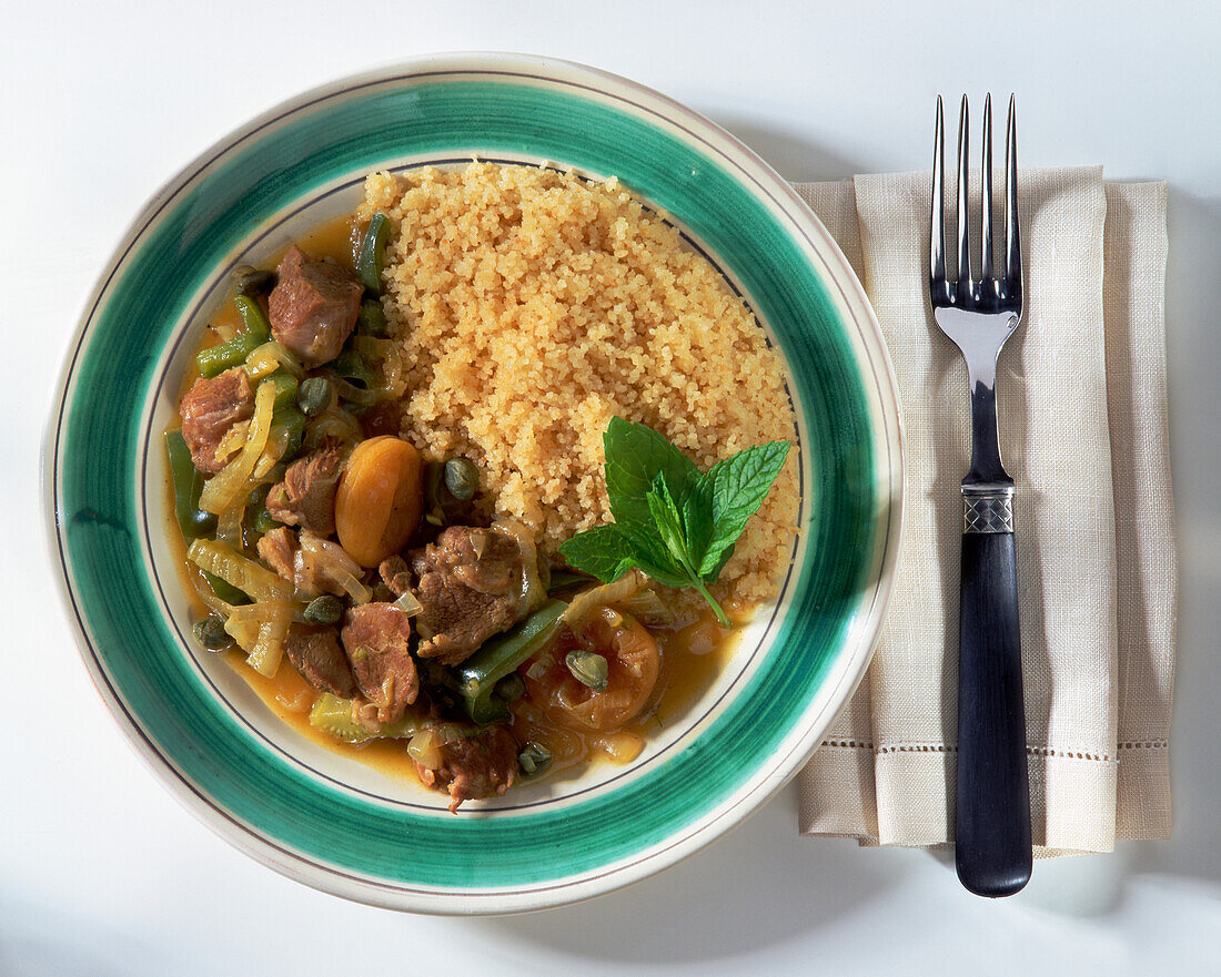 Lamb tagine with couscous, garnished with mint sprig
