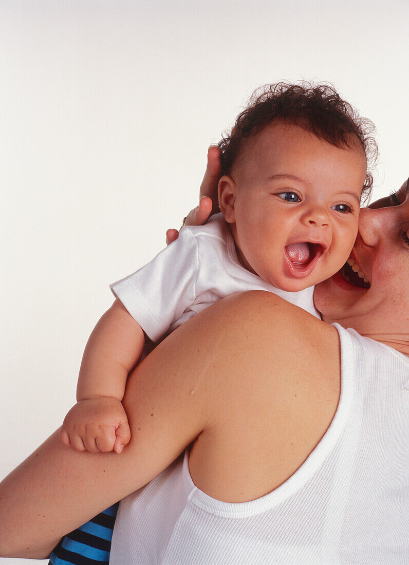 Woman holding a baby boy in white shirt with mouth wide open