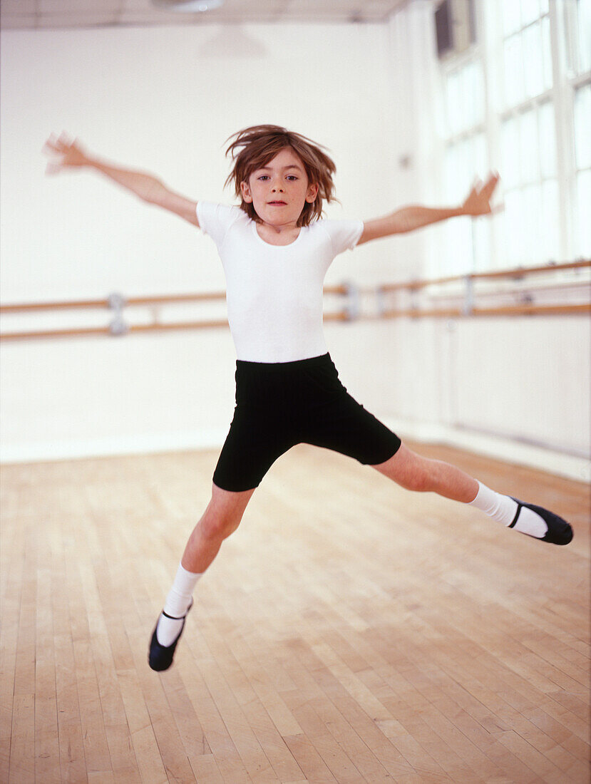Young male dancer leaping across a dance studio