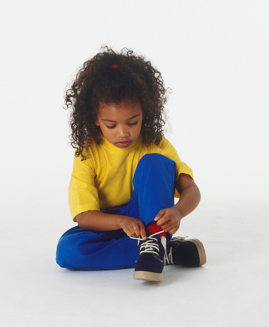 Girl sitting on the floor tying her shoe laces