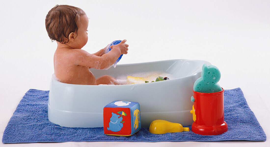 Baby having bubble bath in child's bathtub