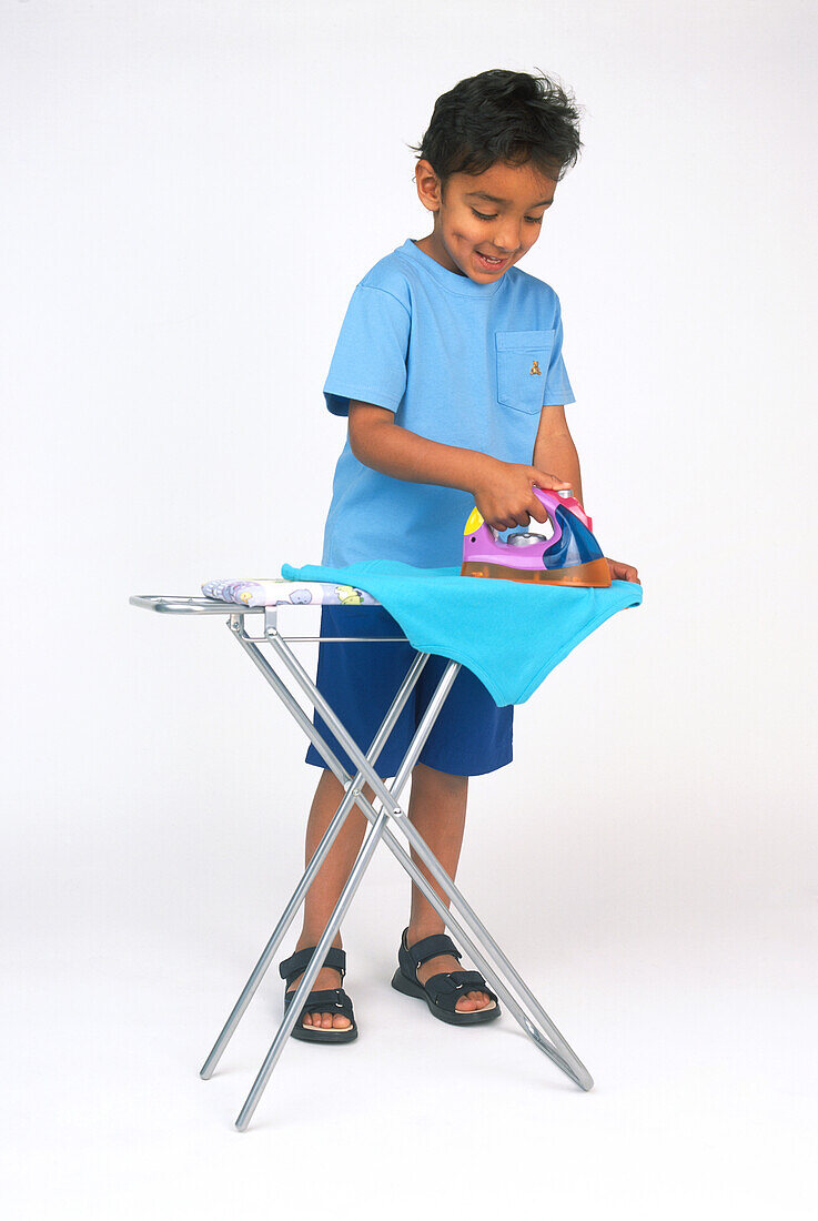 Boy pressing shirt with toy iron
