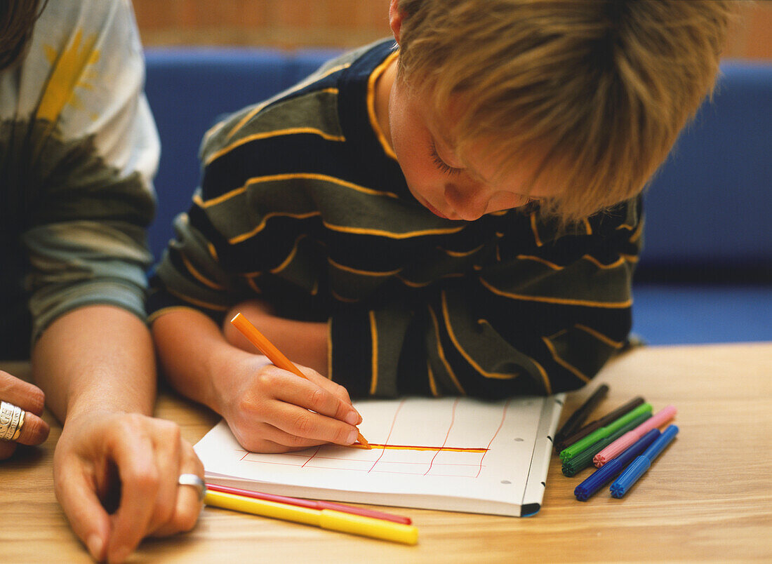 Boy drawing a grid in a note book.