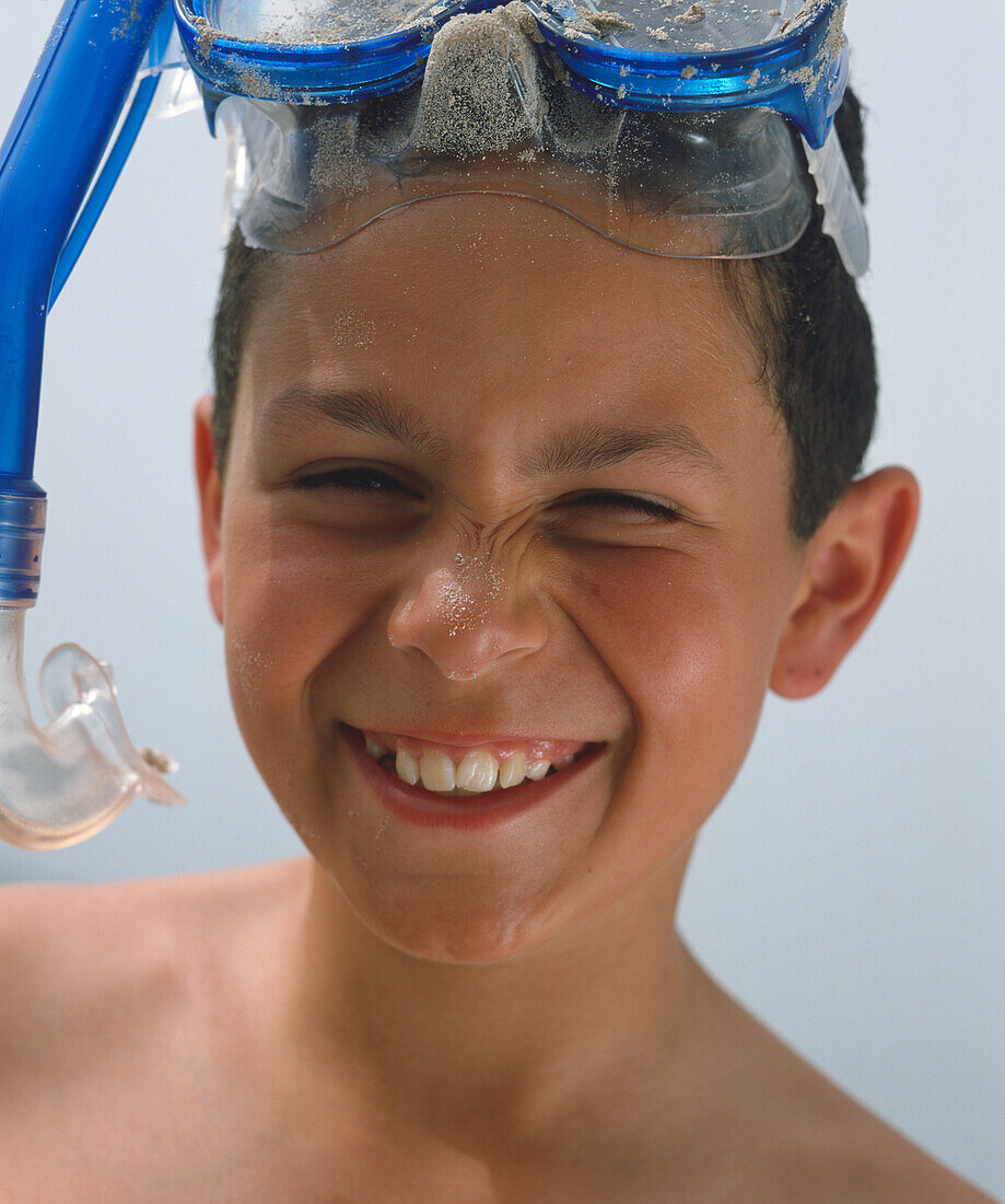 Smiling boy with snorkling mask and sand grains on his nose