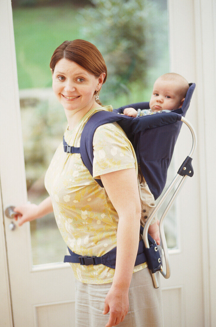 Woman holding baby in soft pack on her back
