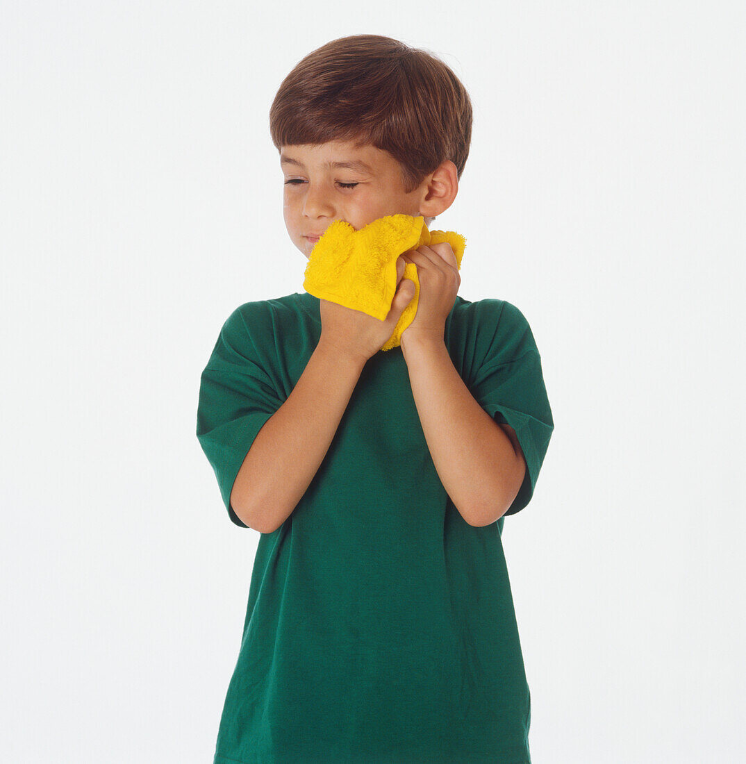 Boy washing his face with a yellow flannel