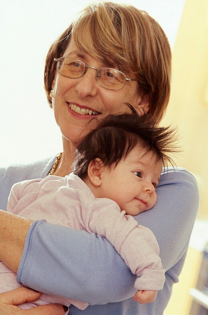 Woman holding smiling baby girl close to her shoulder
