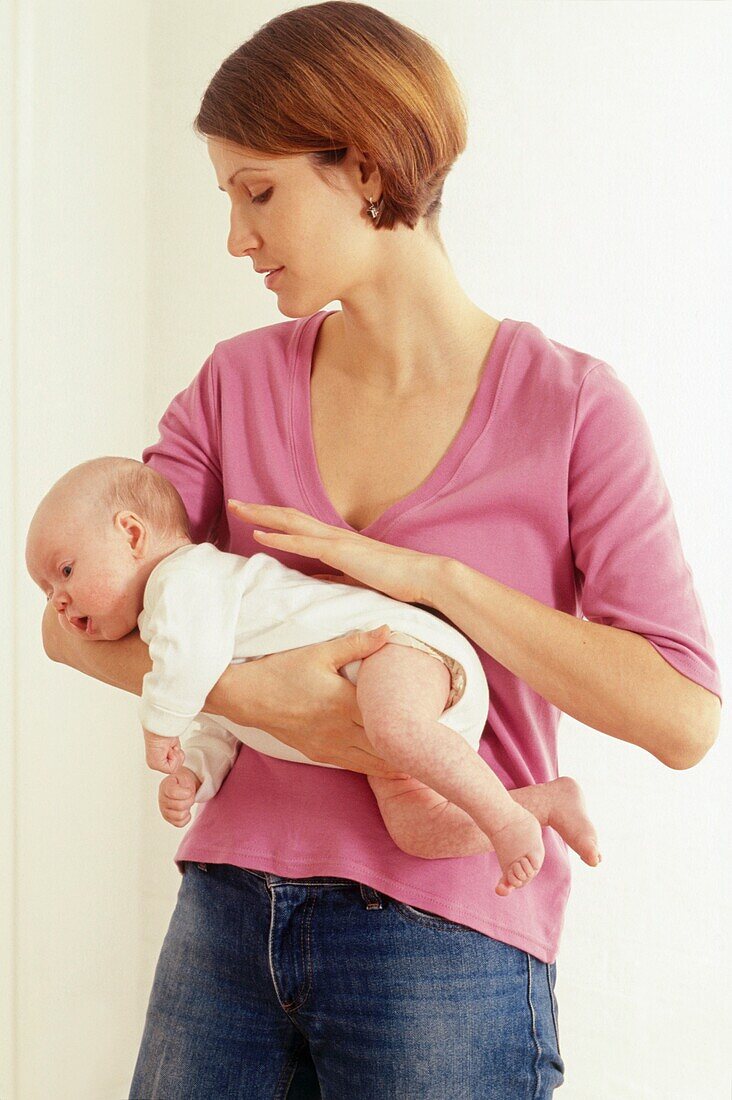 Woman patting the back of a newborn held on her forearm