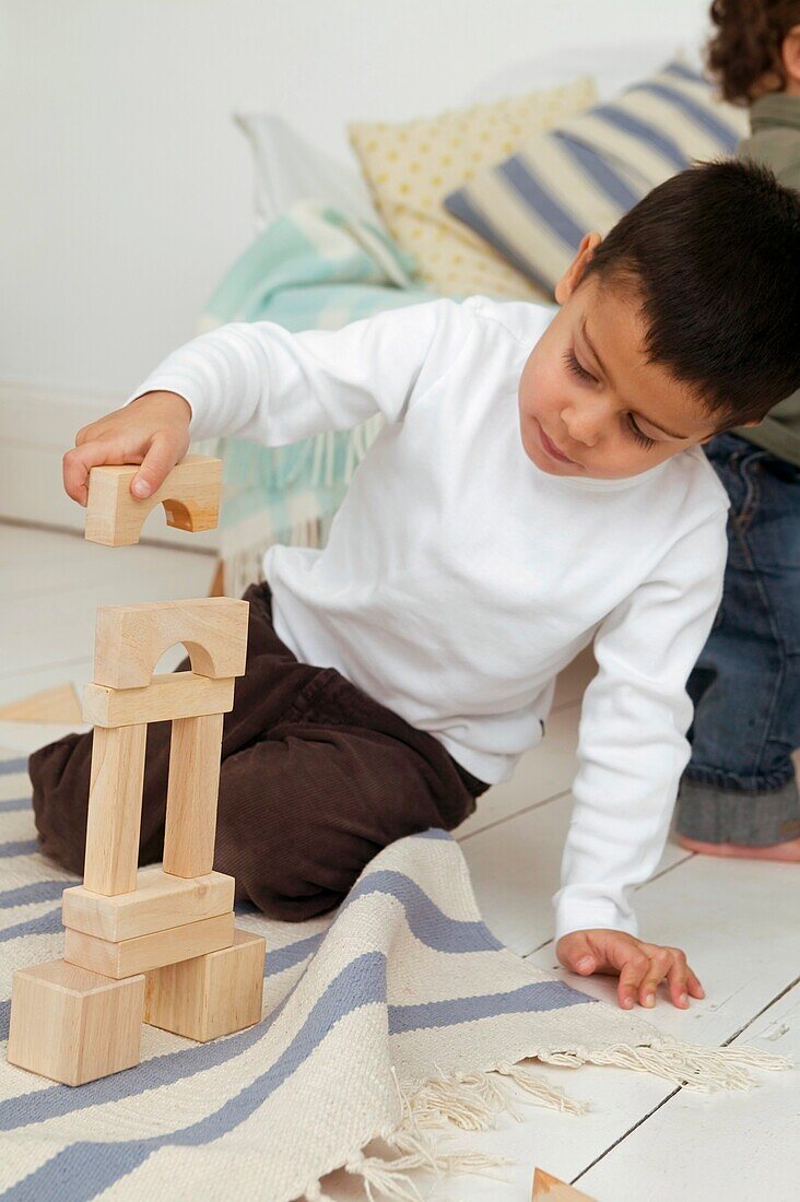 Boy sitting on floor stacking wooden blocks