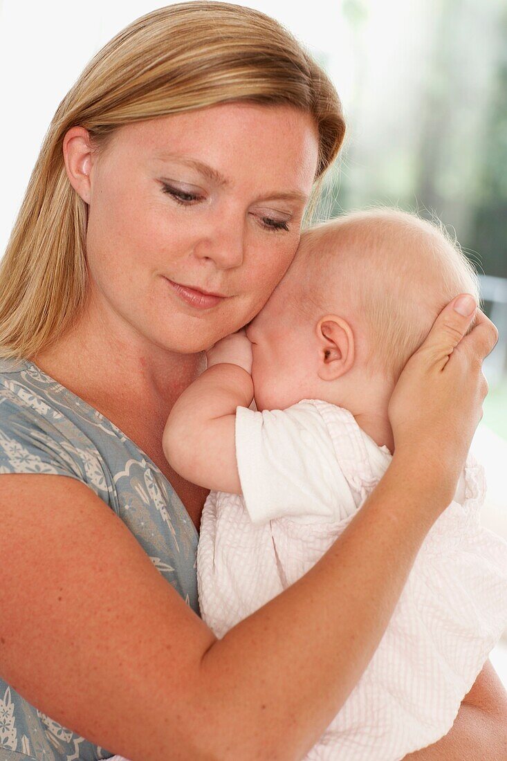 Baby girl rubbing her eyes being held by woman