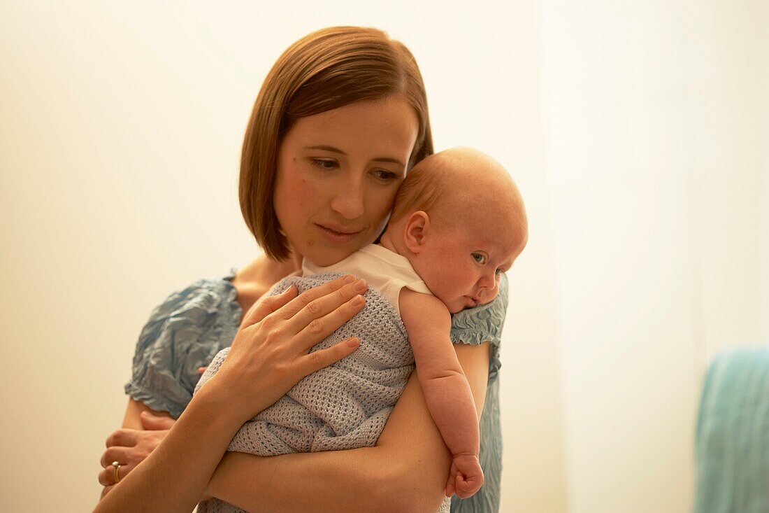 Baby girl resting her head on a woman's shoulder