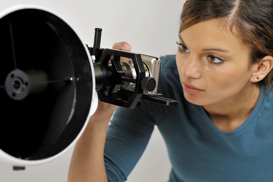 Woman using camera to take photos through telescope lens