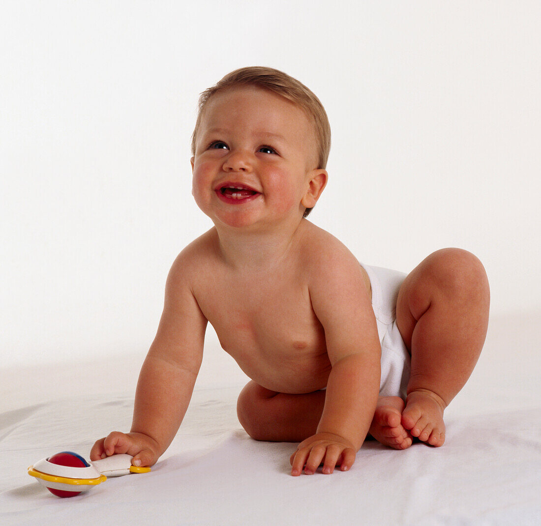 Smiling baby boy holding rattle in hand