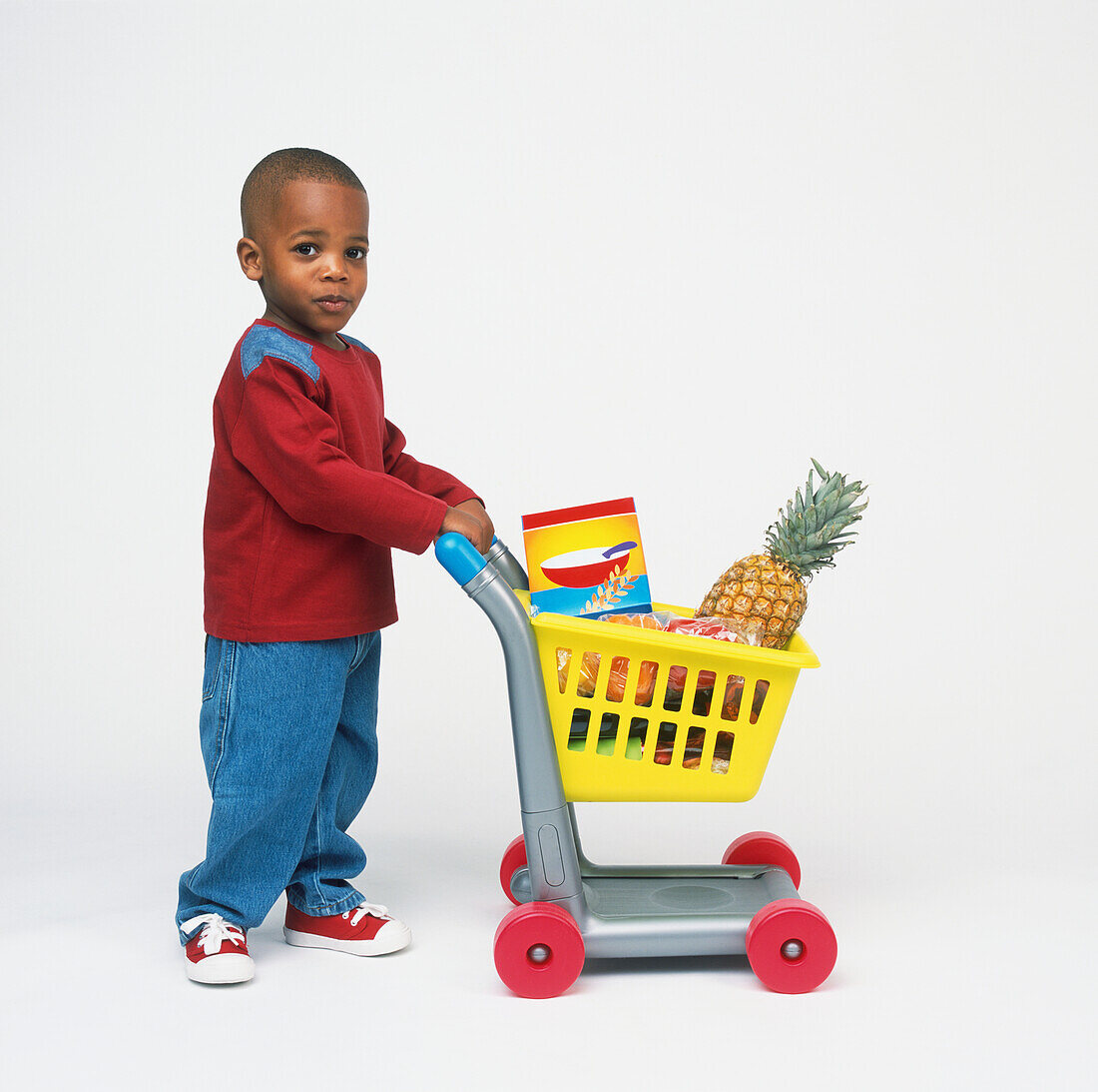 Child pushing a toy shopping trolley