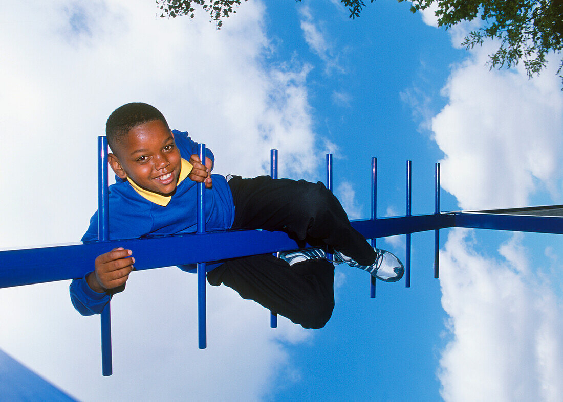 Smiling boy in school uniform on top of climbing frame