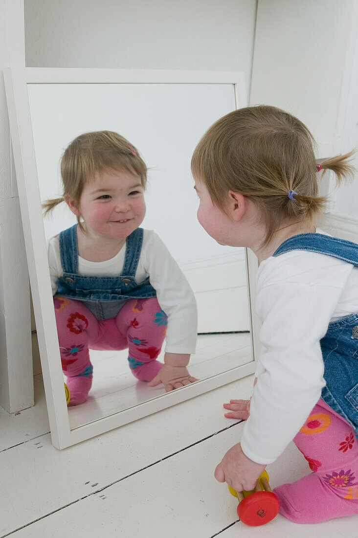 Smiling girl crouching and looking in mirror