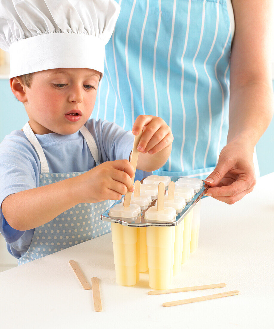 Boy putting lolly sticks into ice lolly mould