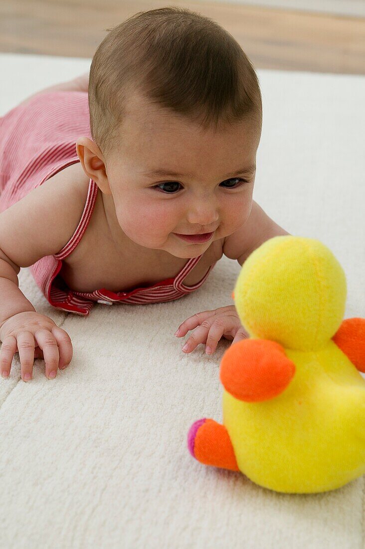 Smiling baby girl looking at toy duck
