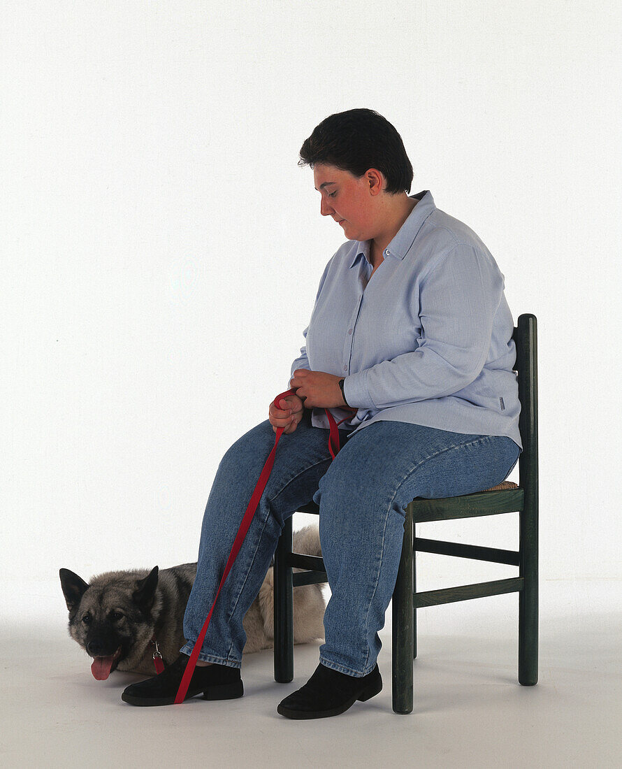 Woman sat on chair with dog on lead at her heel