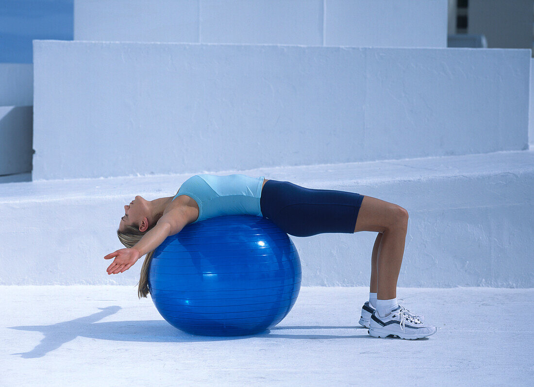 Woman lying back on an exercise ball with arms outstretched