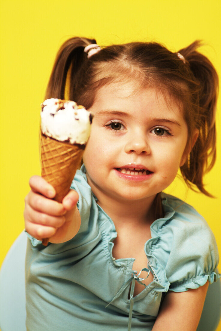 Girl sitting on a blue seat eating an ice cream cone