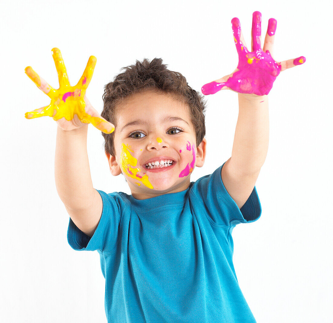 Boy with yellow and pink paint on his hands and face