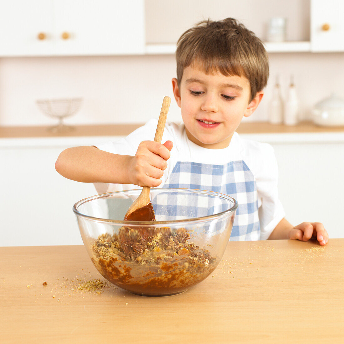 Boy stirring mixture in glass bowl with wooden spoon