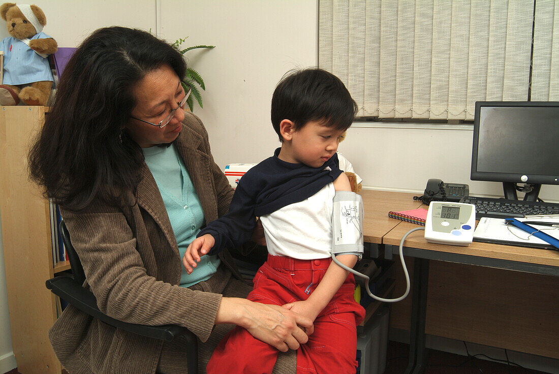 Boy sitting on woman's lap and wearing blood pressure meter