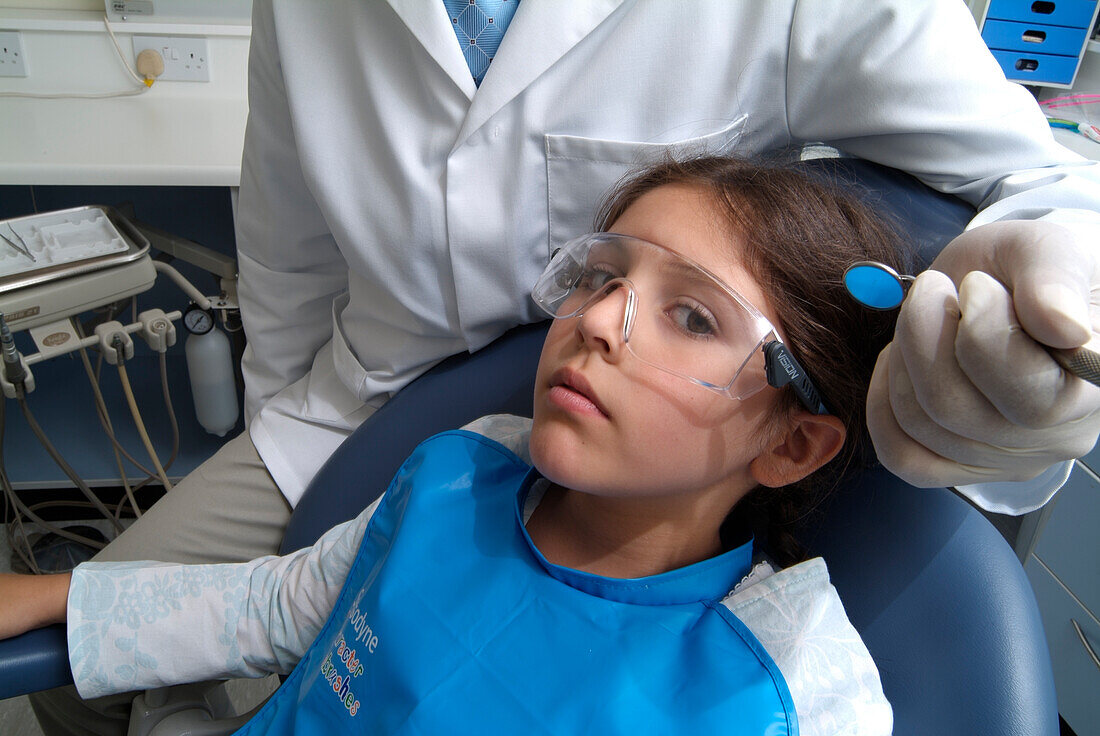 Girl sitting in dentist's chair with a dentist behind her