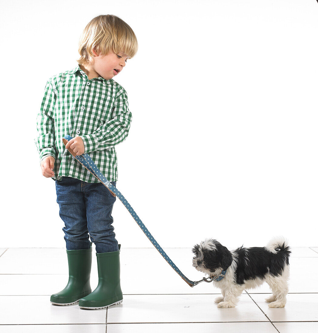 Young boy holding a puppy by a lead