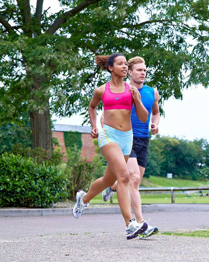 Man and woman running through a park
