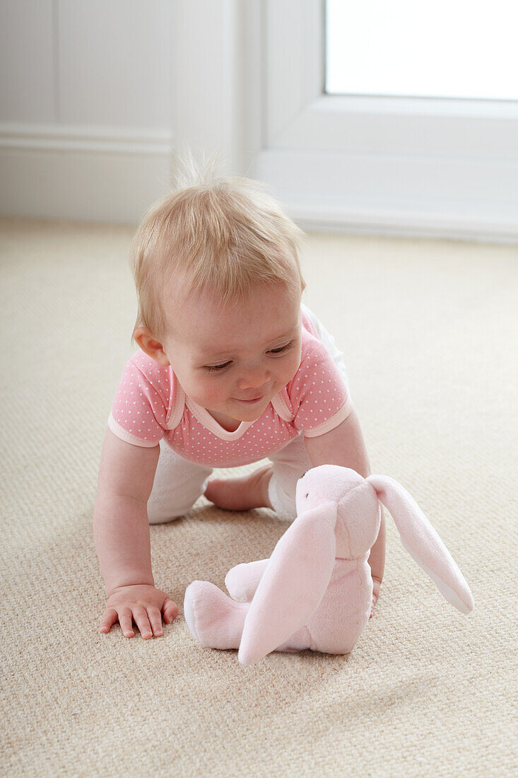 Baby girl with rabbit soft toy