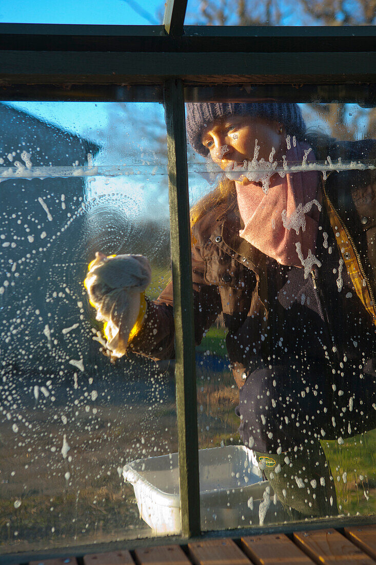 Woman cleaning the windows of a greenhouse