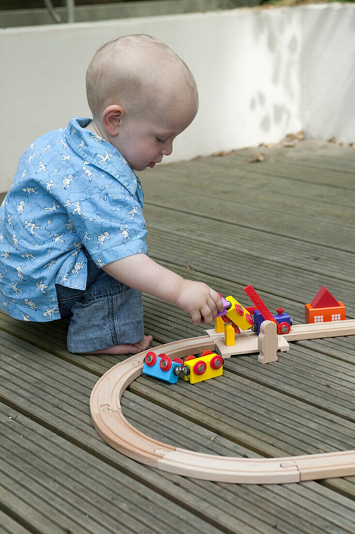 Baby boy playing with toy railway and train