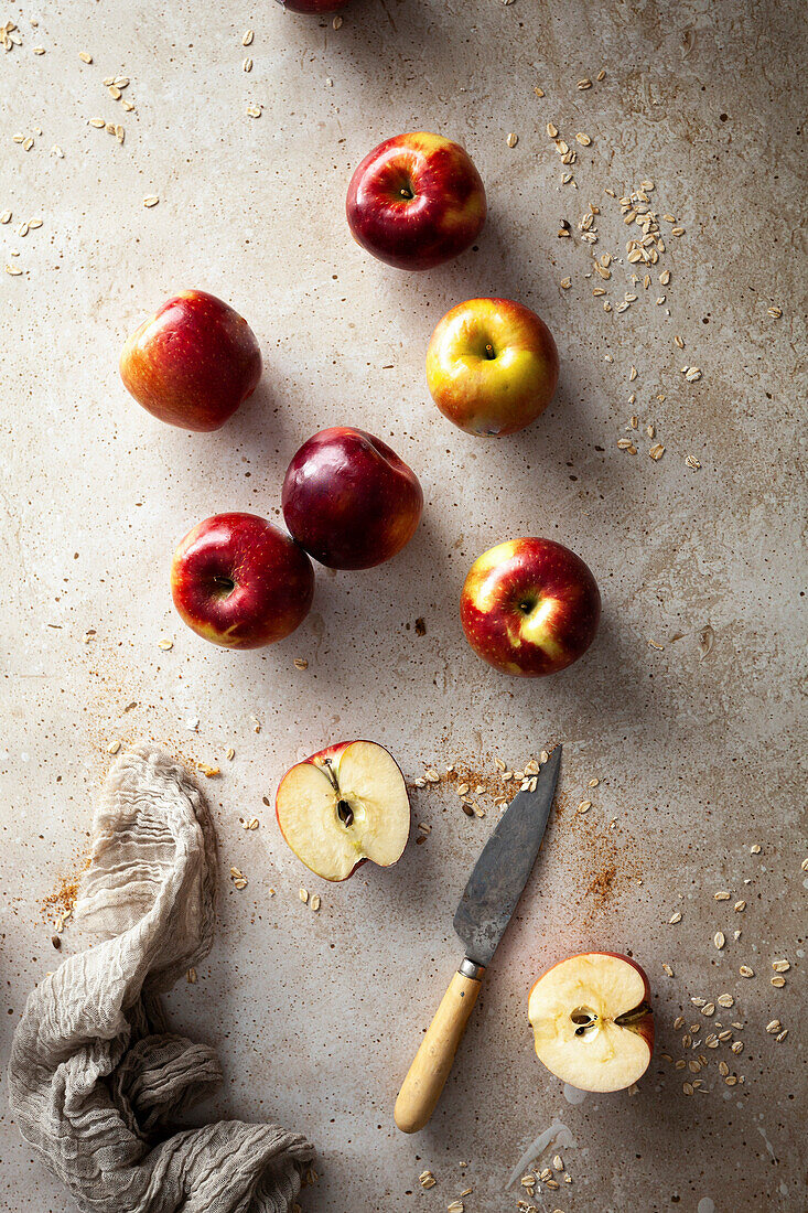 Rote Äpfel, ganz und halbiert mit Messer auf Steinuntergrund