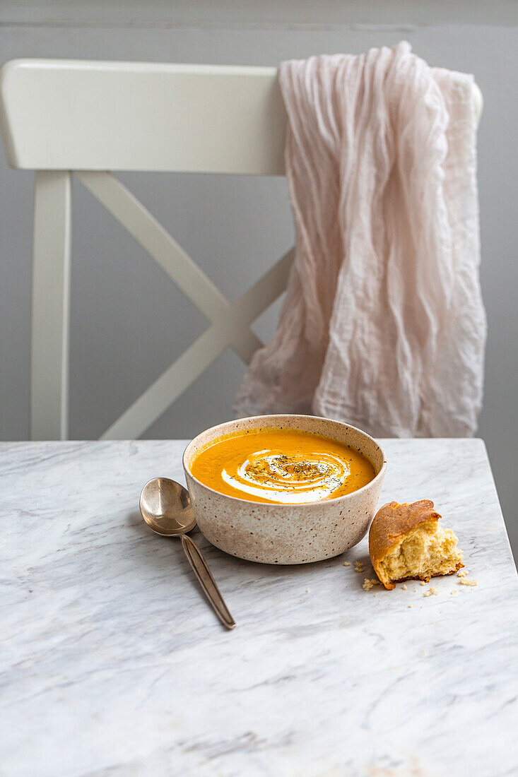 Bowl of pumpkin soup on a white marble surface