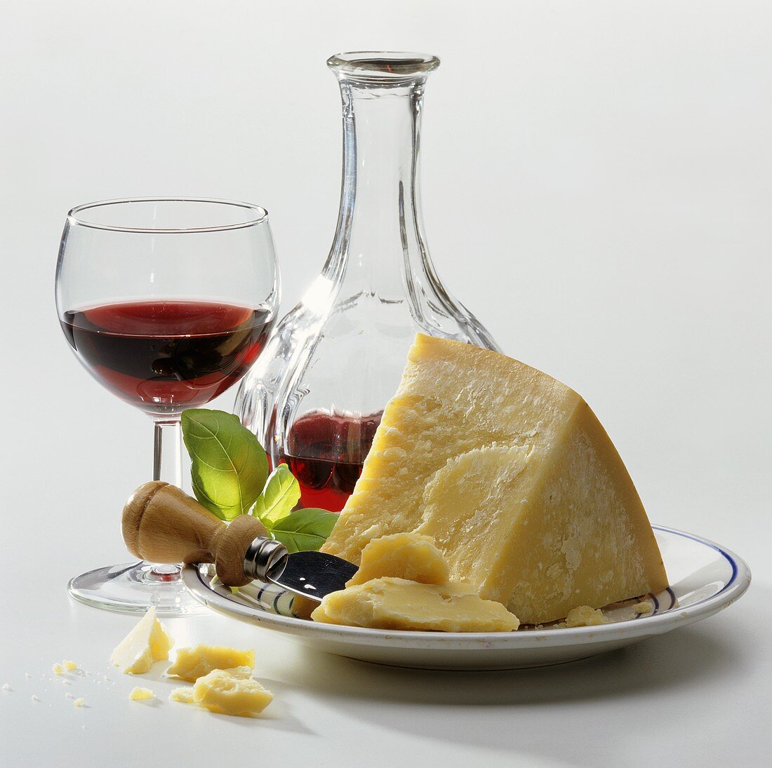 A piece of Parmesan on plate, décor: red wine glass & bottle