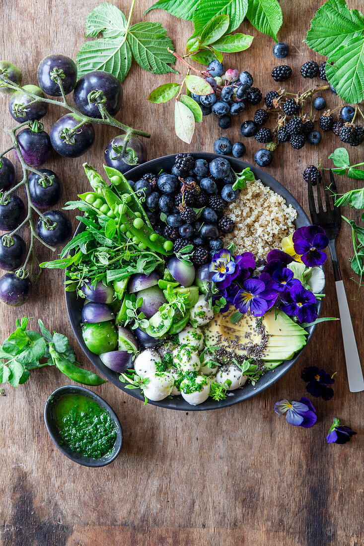 Beeren-Avocado-Bowl mit Quinoa, grünen Tomaten und grünem Kräuteröl