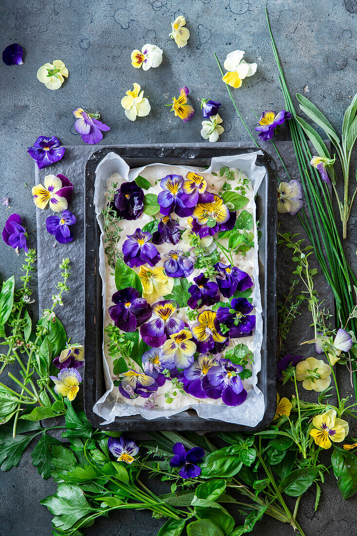 Focaccia with herbs and violet flowers before baking