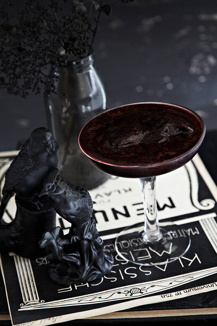 Dark cocktail with ice in a martini glass