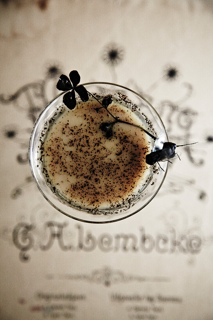 Cocktail glass with dark decorations and a sprinkling of spices